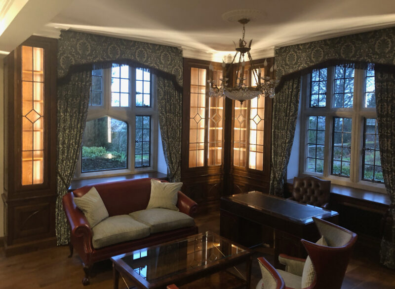 A fitted office bookcase and cupboards with leaded glass doors, by Reeve & Co Interiors
