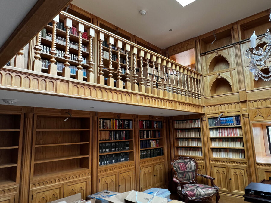 A barley-twist staircase rising through a fitted library of oak bookcases, made by Reeve & Co Interiors