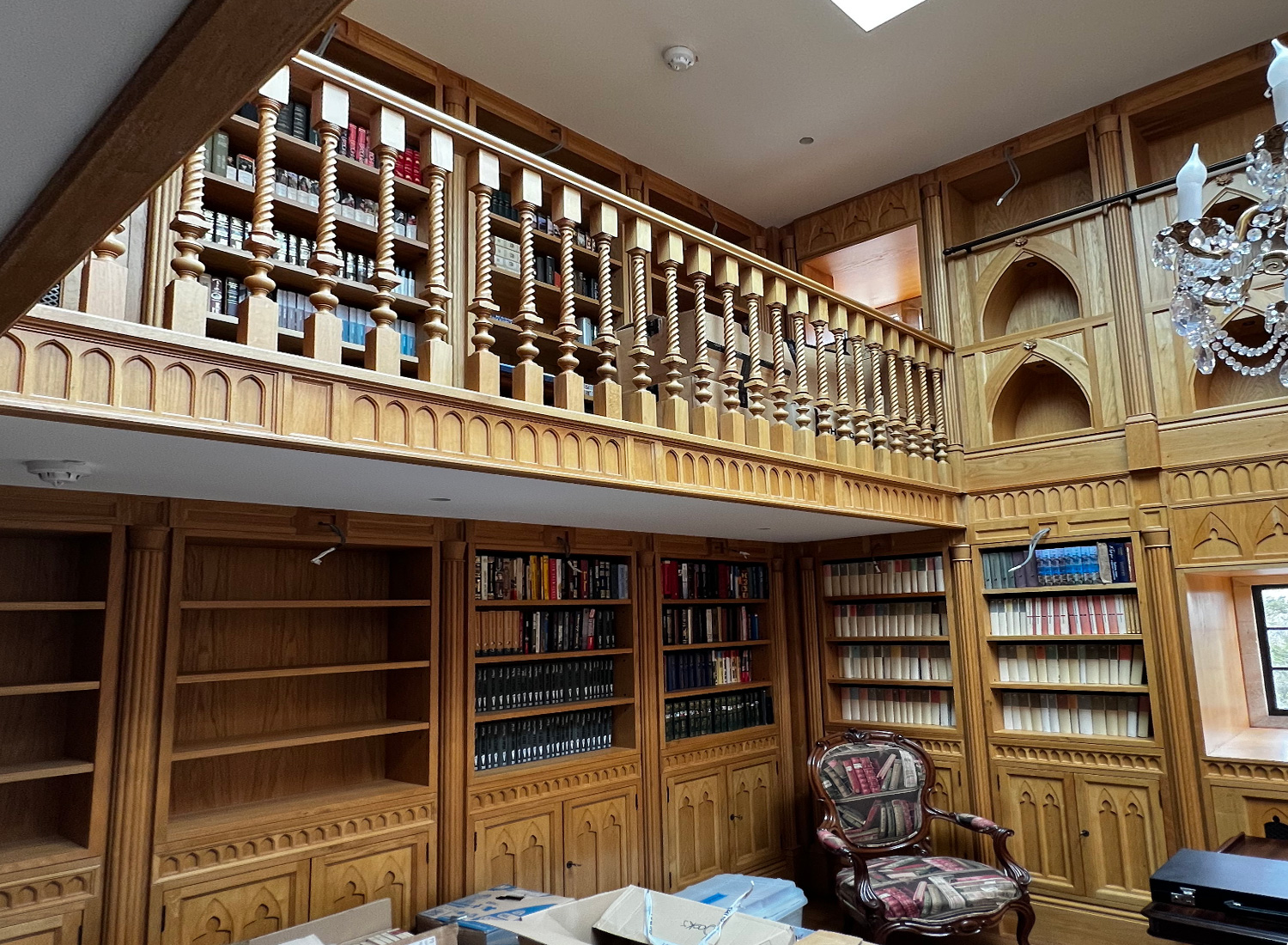 A barley-twist staircase rising through a fitted library of oak bookcases, made by Reeve & Co Interiors