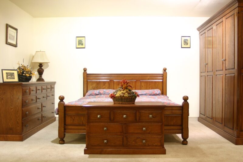 Panelled oak bed with a matching wardrobe and chest of drawers in a bedroom