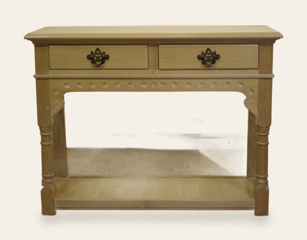 A carved two-drawer side table finished in limed oak