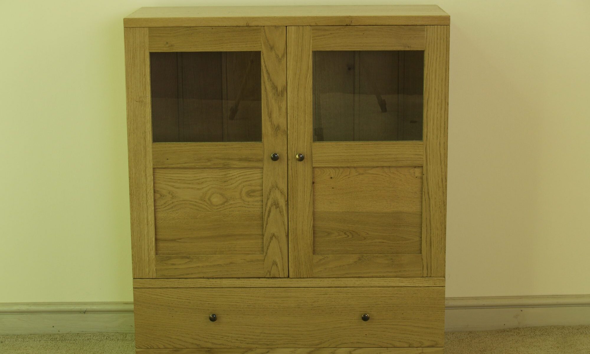 Contemporary two glass door cabinet with one drawer, front view — handmade by Bryn Hall in Suffolk